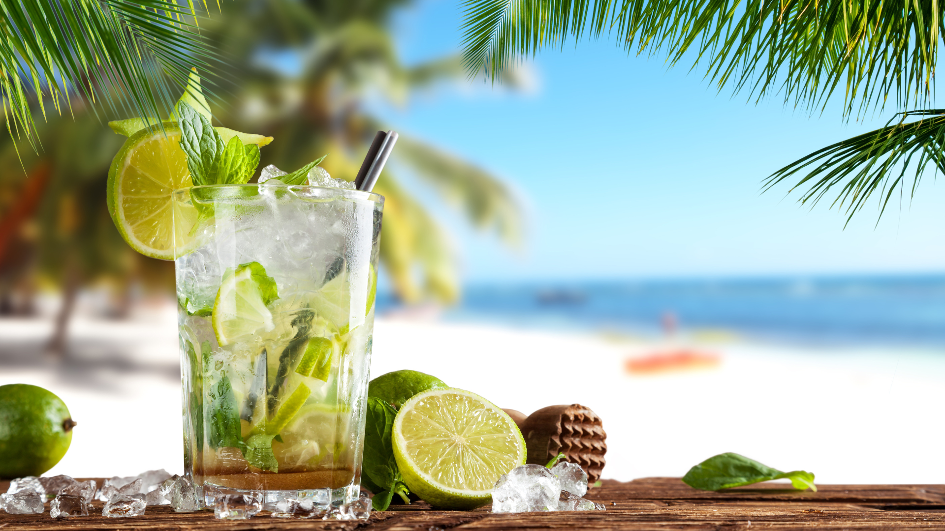 Mojito on a table with limes with a beach in the background