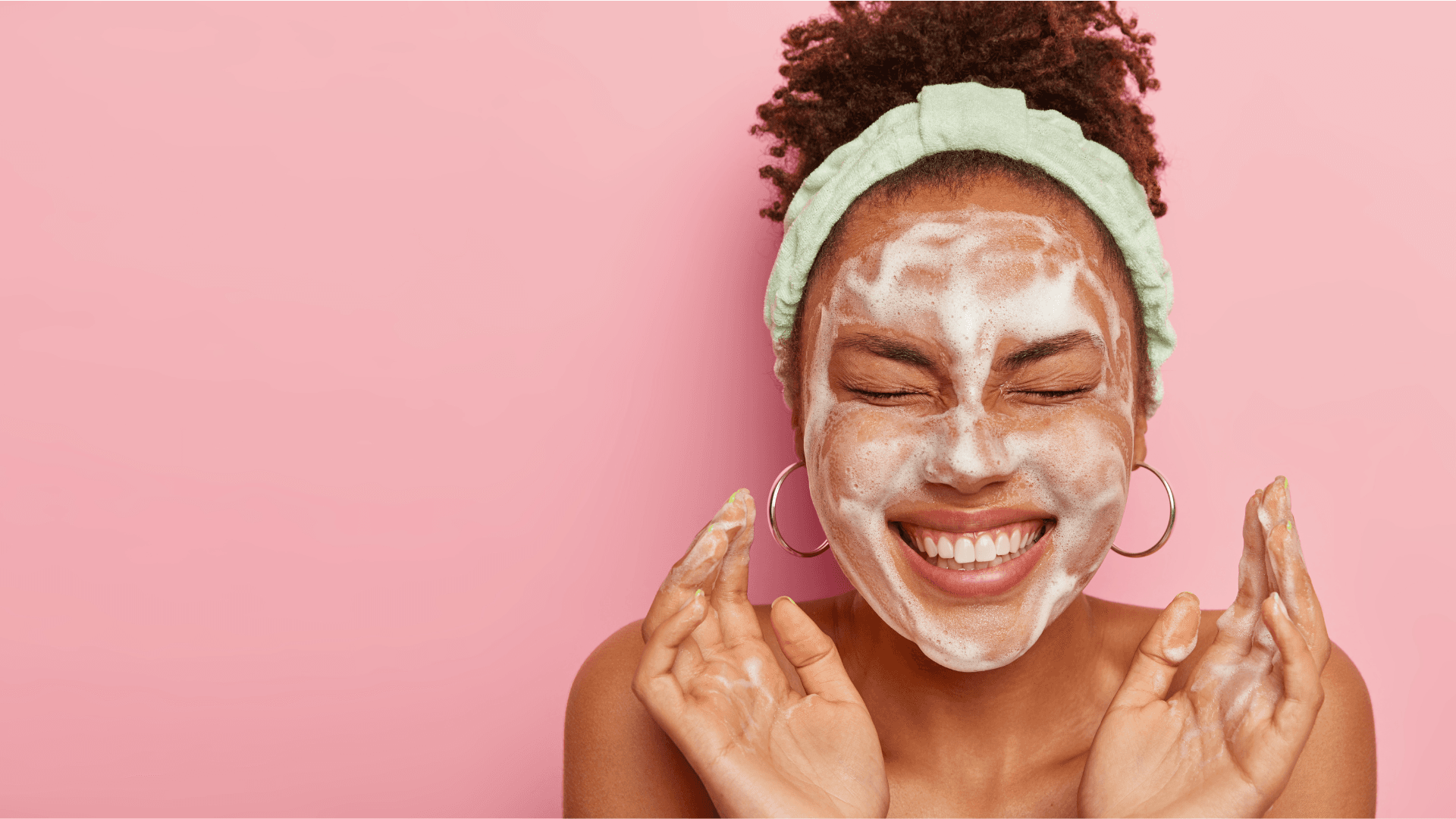 Smiling woman with a foaming cleanser on her face