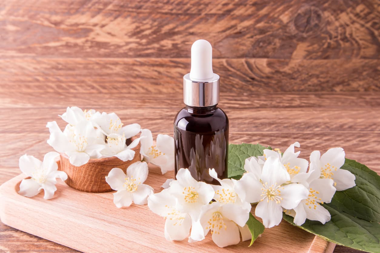 Brown dropper bottle surrounded by jasmine flowers