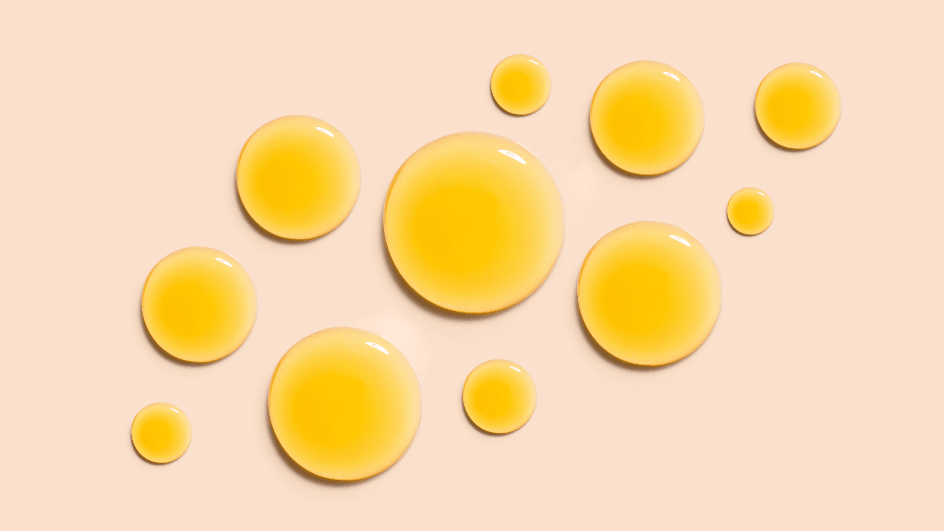 Yellow oil drops on a beige background