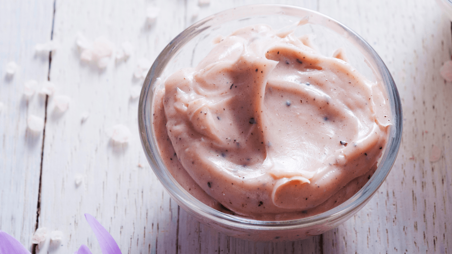 Pink exfoliating cream in a bowl on a table