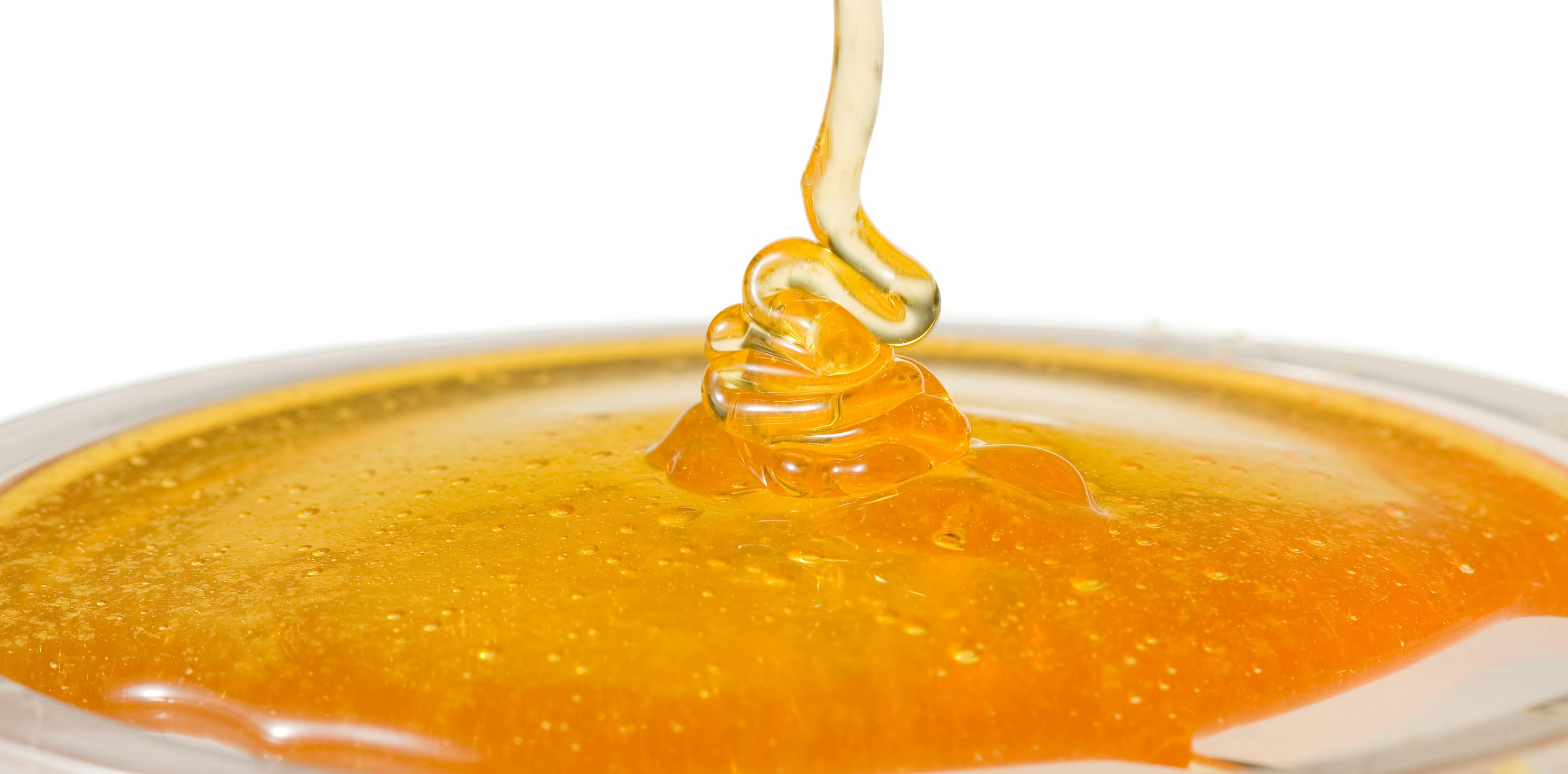 Honey coloured gel being poured over a white background