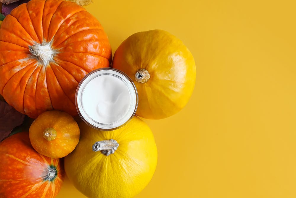 White cream surrounded by pumpkins on a yellow background